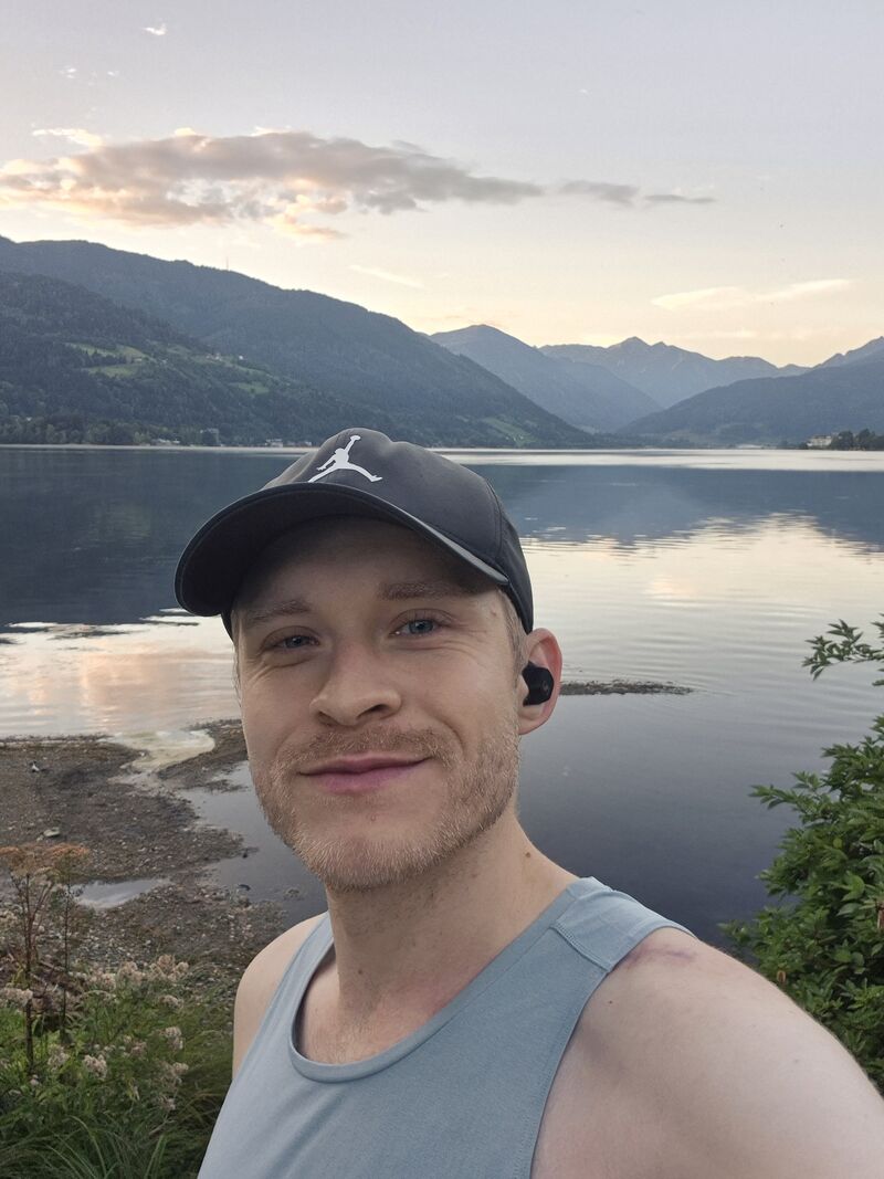 Michi mit Kappe vor einem Bergsee im Morgenlicht