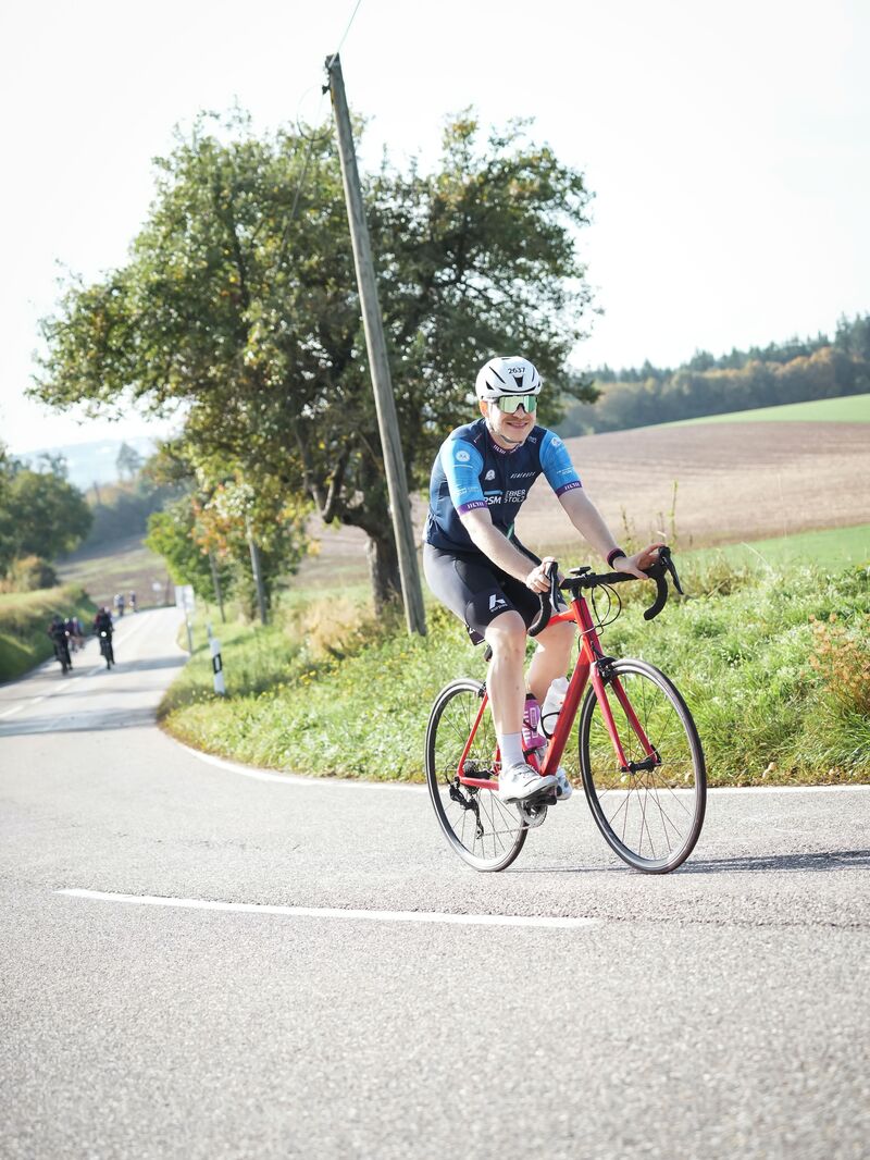 Michi auf dem Rennrad in einer Kurve zwischen Feldern